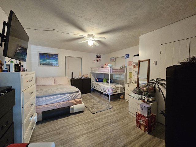 bedroom featuring ceiling fan, hardwood / wood-style floors, and a textured ceiling