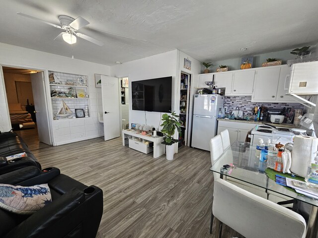 kitchen featuring ceiling fan, white cabinetry, backsplash, wood-type flooring, and white fridge