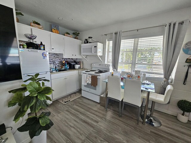 kitchen with hardwood / wood-style floors, white cabinetry, sink, decorative backsplash, and white appliances