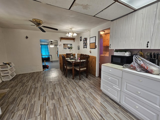 kitchen with ceiling fan with notable chandelier, white cabinets, and light wood-type flooring