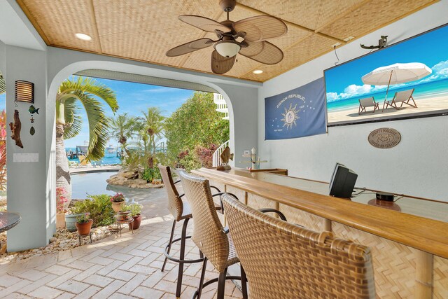 view of patio / terrace with an outdoor bar, ceiling fan, and a water view