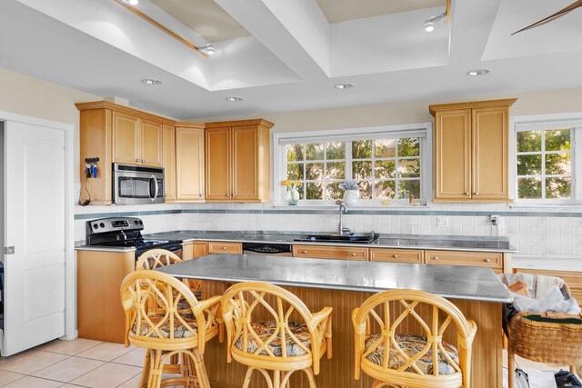 kitchen with stainless steel appliances, a breakfast bar, sink, and backsplash