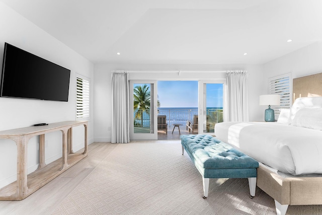 bedroom featuring access to exterior, light hardwood / wood-style flooring, vaulted ceiling, and a water view