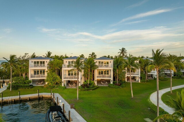 exterior space featuring a balcony, a water view, and a lawn