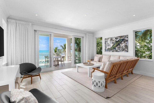 living room featuring light hardwood / wood-style flooring, ornamental molding, and a water view