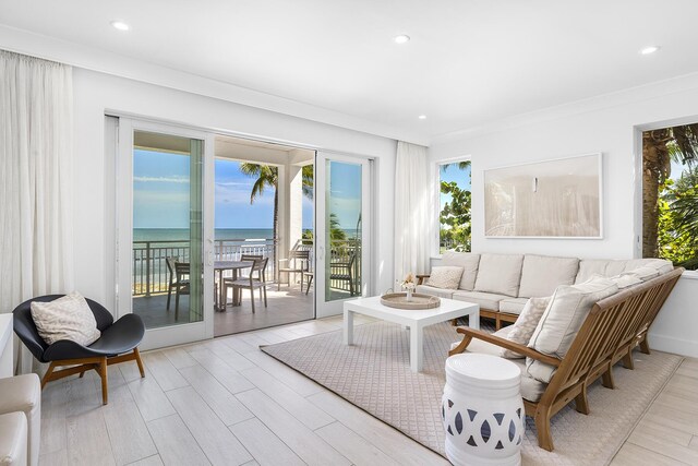 living room featuring light hardwood / wood-style flooring, ornamental molding, and a water view