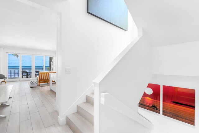 stairs with hardwood / wood-style flooring and a water view