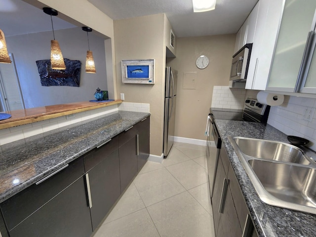88500 Overseas Hwy Unit 301, Tavernier, FL 33070 - kitchen with appliances with stainless steel finishes, light tile patterned floors, backsplash, dark stone countertops, and hanging light fixtures