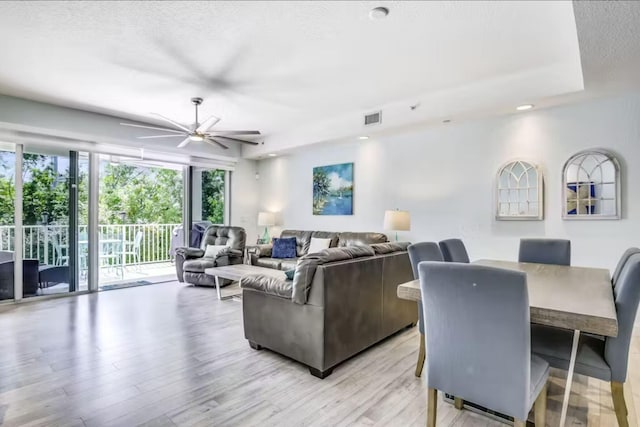 living room with ceiling fan, light hardwood / wood-style floors, and a textured ceiling