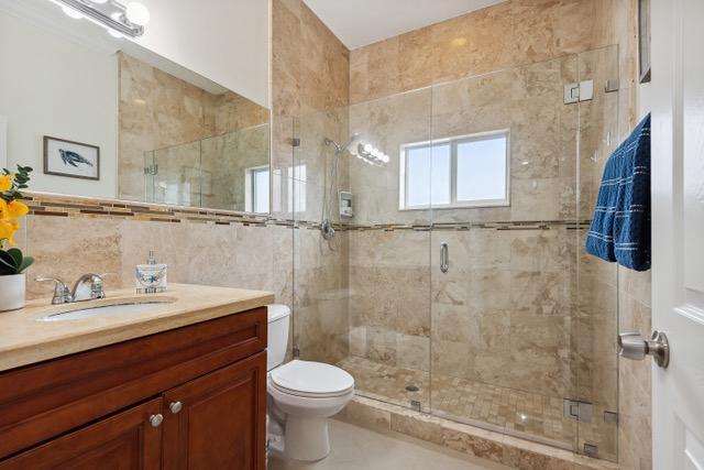 911 Red Bird Rd, Key Largo, FL 33037 - bathroom with vanity, tile walls, a shower stall, and tile patterned floors