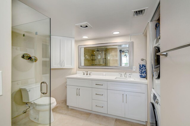8302 Marina Villas Dr Unit 8302, Duck, FL 33050 - bathroom featuring vanity, stacked washer / drying machine, a shower with shower door, tile patterned floors, and toilet