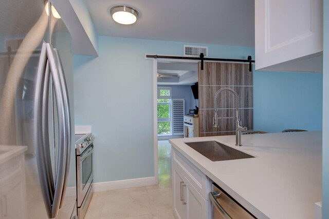 8302 Marina Villas Dr Unit 8302, Duck, FL 33050 - kitchen featuring stainless steel appliances, white cabinetry, a barn door, and sink