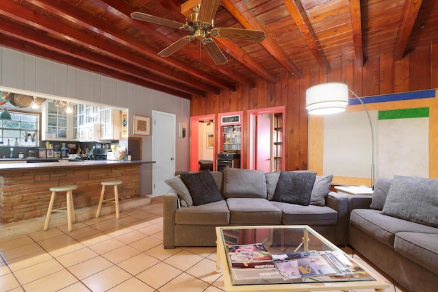 living room with light tile patterned floors, wood ceiling, wooden walls, and beamed ceiling