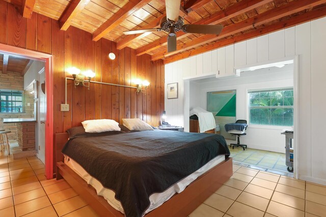 bedroom featuring light tile patterned flooring, beamed ceiling, wood walls, and wooden ceiling