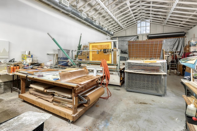 miscellaneous room with vaulted ceiling, a workshop area, and concrete floors