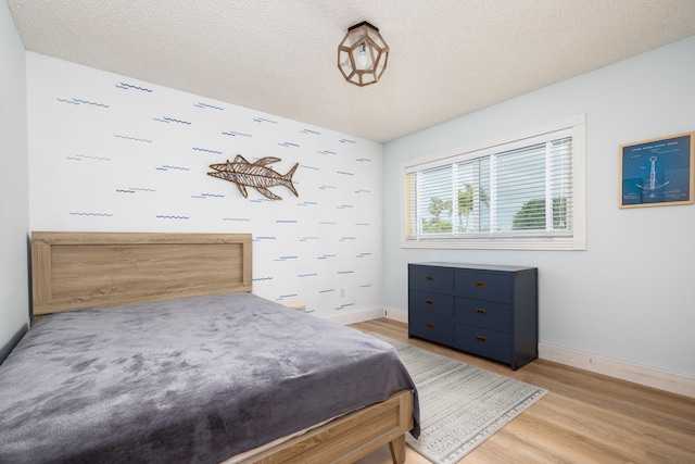 bedroom with light hardwood / wood-style flooring and a textured ceiling
