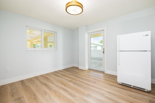 unfurnished room with light hardwood / wood-style floors and a textured ceiling