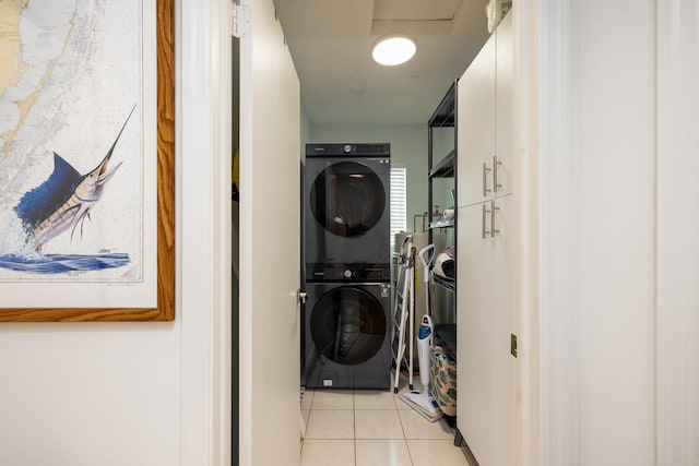 clothes washing area featuring stacked washing maching and dryer and light tile patterned floors