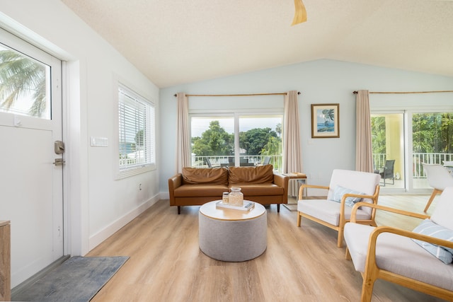living room with light hardwood / wood-style floors, vaulted ceiling, and a textured ceiling