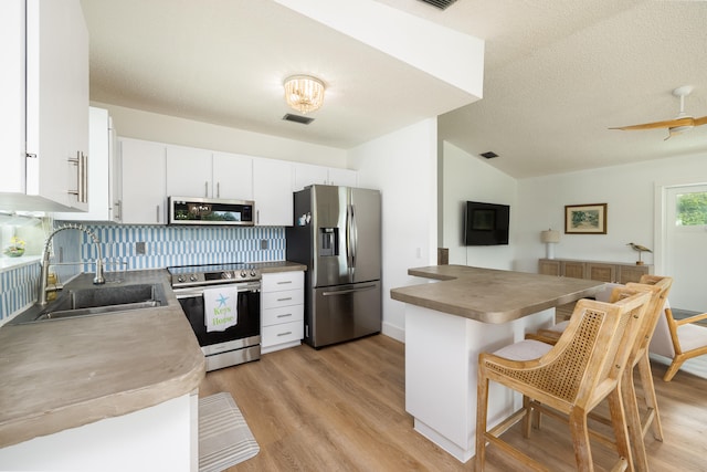 kitchen featuring sink, tasteful backsplash, appliances with stainless steel finishes, a kitchen breakfast bar, and white cabinets