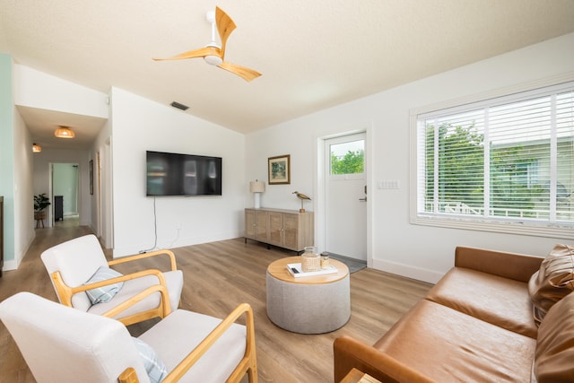 living room featuring a textured ceiling, vaulted ceiling, ceiling fan, and light wood-type flooring