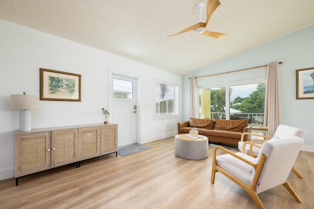 living room with lofted ceiling, ceiling fan, a textured ceiling, and light wood-type flooring