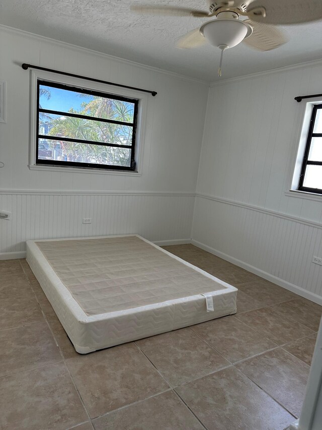 16 Shoreland Dr, Key Largo, FL 33037 - unfurnished bedroom featuring ceiling fan, a decorative wall, ornamental molding, and tile patterned flooring