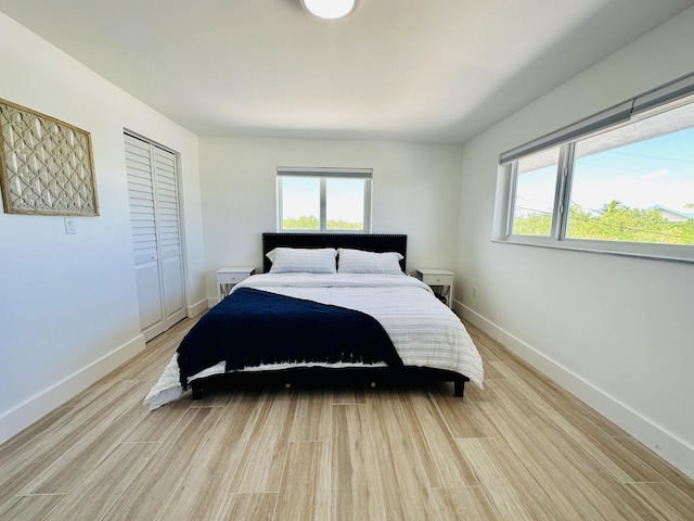 bedroom featuring multiple windows, light hardwood / wood-style floors, and a closet