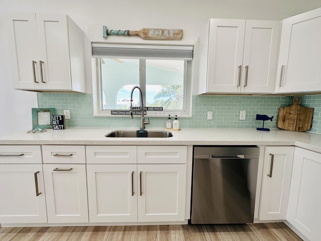 kitchen featuring sink, stainless steel dishwasher, white cabinets, and light wood-type flooring