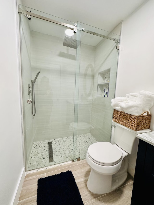 bathroom with vanity, a shower with shower door, and toilet