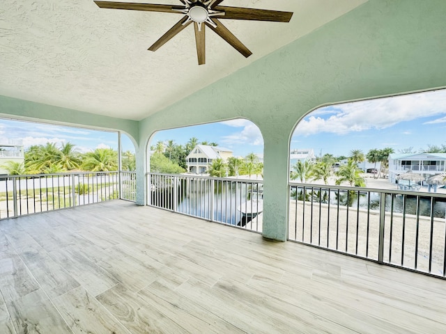 view of patio featuring a water view, ceiling fan, and a balcony