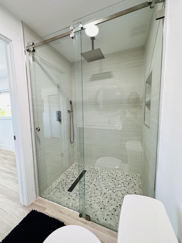 bathroom with a shower with door and toilet