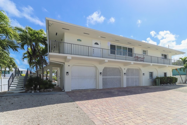 1323 Hudgins Dr, Summerland, FL 33042 - view of front facade featuring stairway, stucco siding, decorative driveway, and an attached garage