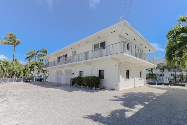 1323 Hudgins Dr, Summerland, FL 33042 - rear view of house featuring a garage, stucco siding, driveway, and a balcony