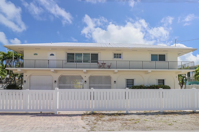 1323 Hudgins Dr, Summerland, FL 33042 - view of front of home with stucco siding, metal roof, a balcony, and a fenced front yard