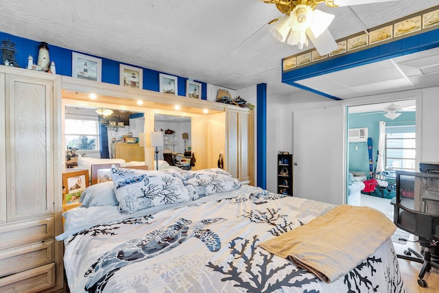 bedroom featuring a wall mounted AC and a ceiling fan