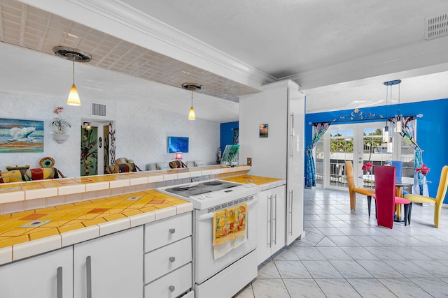 kitchen with visible vents, open floor plan, tile counters, white range with electric stovetop, and white cabinets