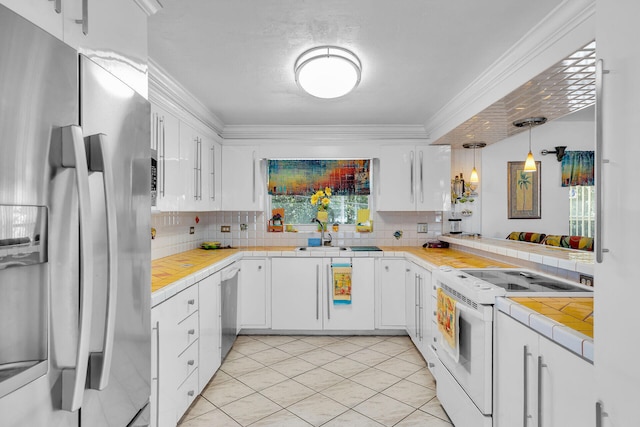 kitchen with tile counters, stainless steel appliances, white cabinetry, decorative backsplash, and ornamental molding