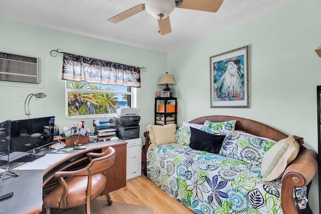 bedroom featuring ceiling fan, light wood finished floors, and a wall mounted air conditioner