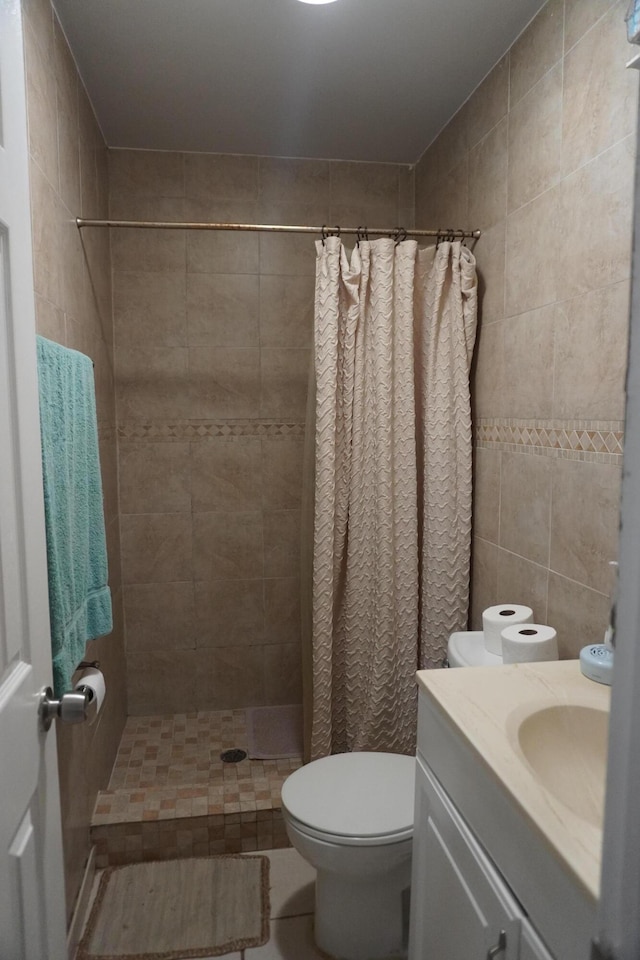 bathroom featuring tile walls, vanity, curtained shower, and toilet