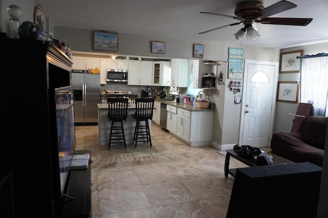 kitchen featuring tasteful backsplash, white cabinets, a kitchen bar, a center island, and stainless steel appliances