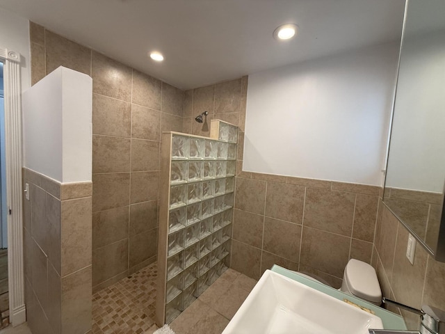 bathroom featuring toilet, tile walls, and tiled shower