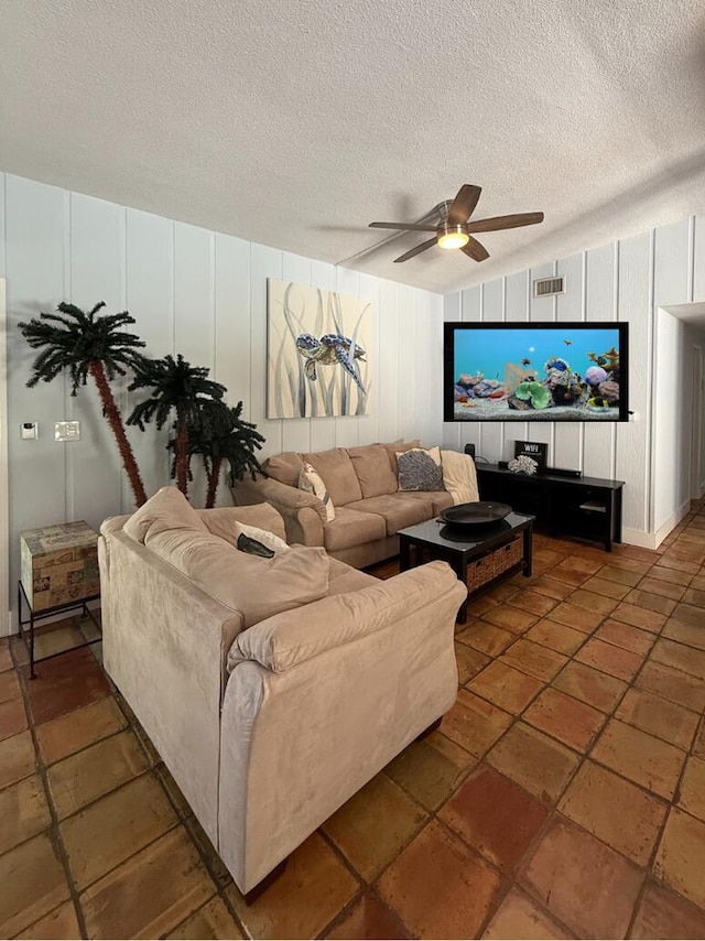 living room with a textured ceiling, vaulted ceiling, and ceiling fan