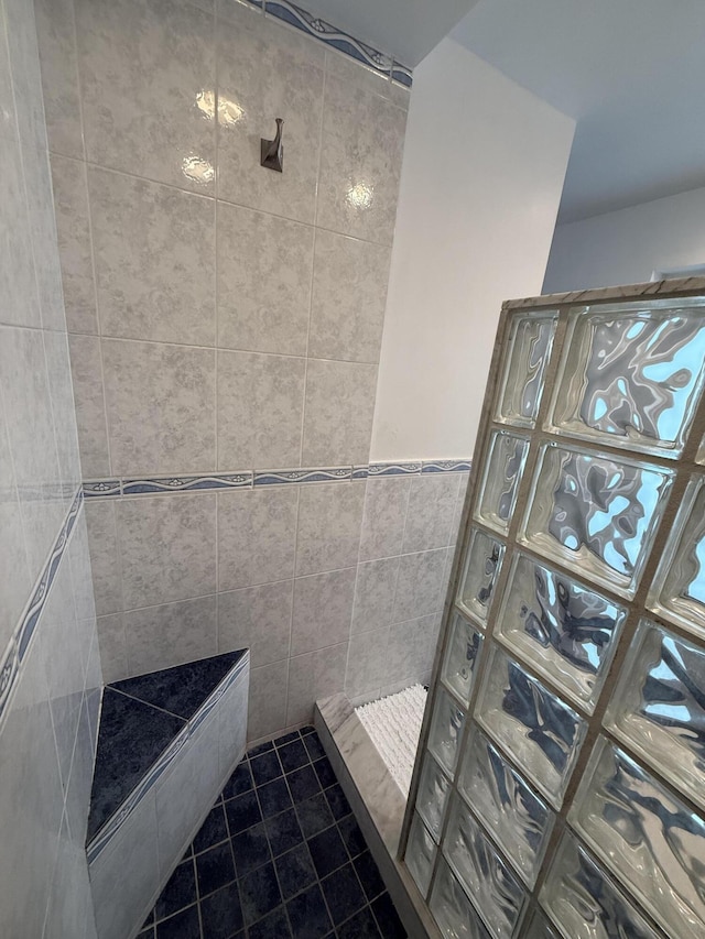 bathroom with tile walls, tile patterned flooring, and tiled shower