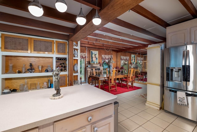 kitchen featuring stainless steel refrigerator with ice dispenser, light countertops, beam ceiling, light tile patterned floors, and wood walls