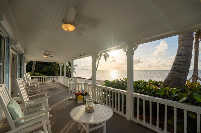 wooden deck with a water view, ceiling fan, and covered porch