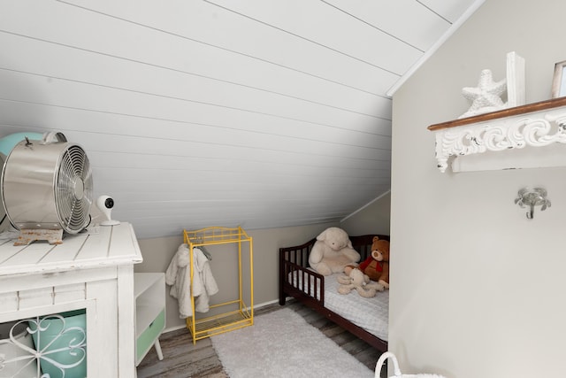 bedroom featuring hardwood / wood-style flooring, a nursery area, and lofted ceiling