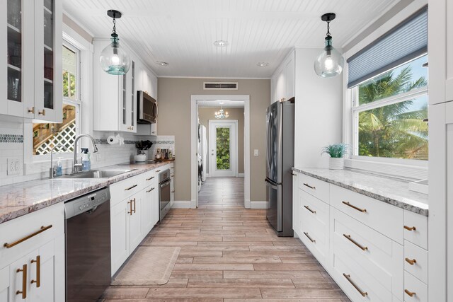 kitchen with white cabinetry, appliances with stainless steel finishes, sink, and hanging light fixtures