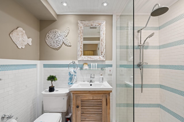 bathroom with vanity, tiled shower, tile walls, and toilet