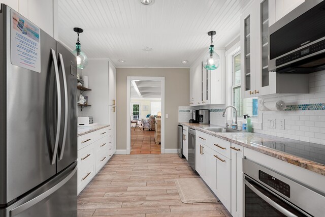 kitchen featuring sink, white cabinetry, decorative light fixtures, stainless steel appliances, and light stone countertops